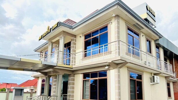A two-story building with a balcony, large windows, and a sign that reads 'Hotel'.