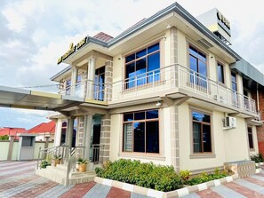 Um edifício de dois andares com varanda, janelas amplas e uma placa com a inscrição 'Hotel'.