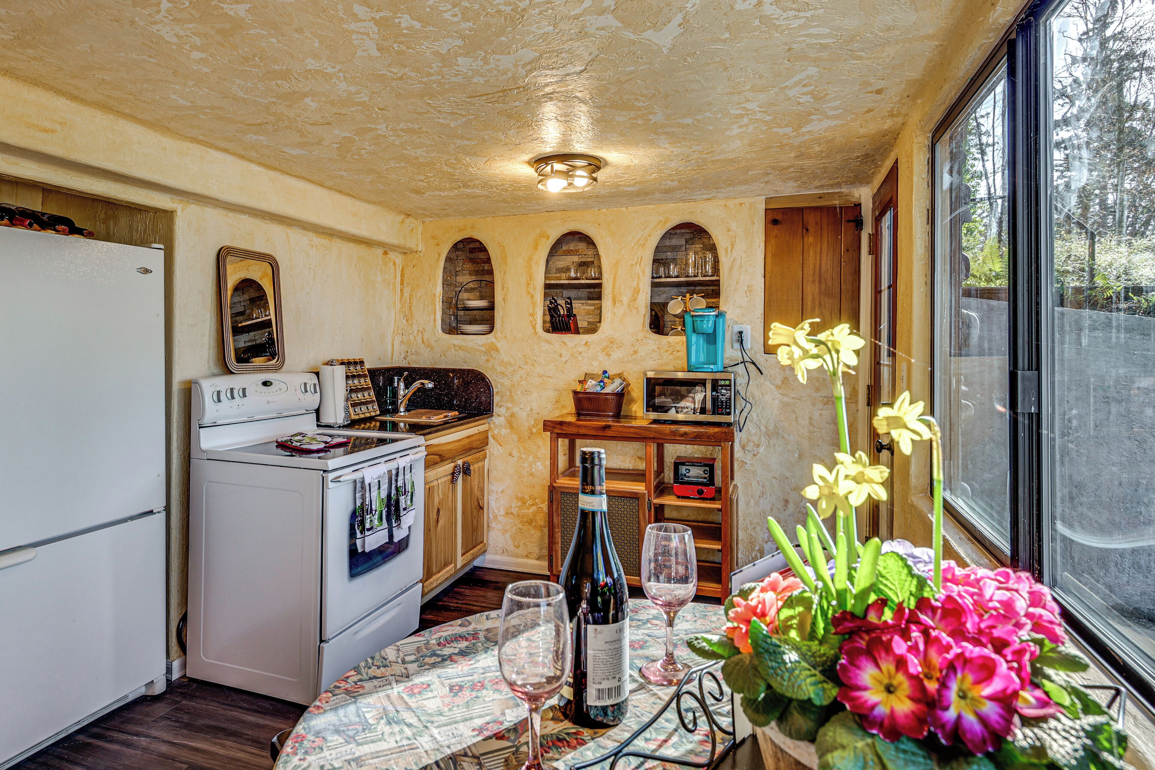 A kitchen with a refrigerator, stove, microwave, and wine bottle.