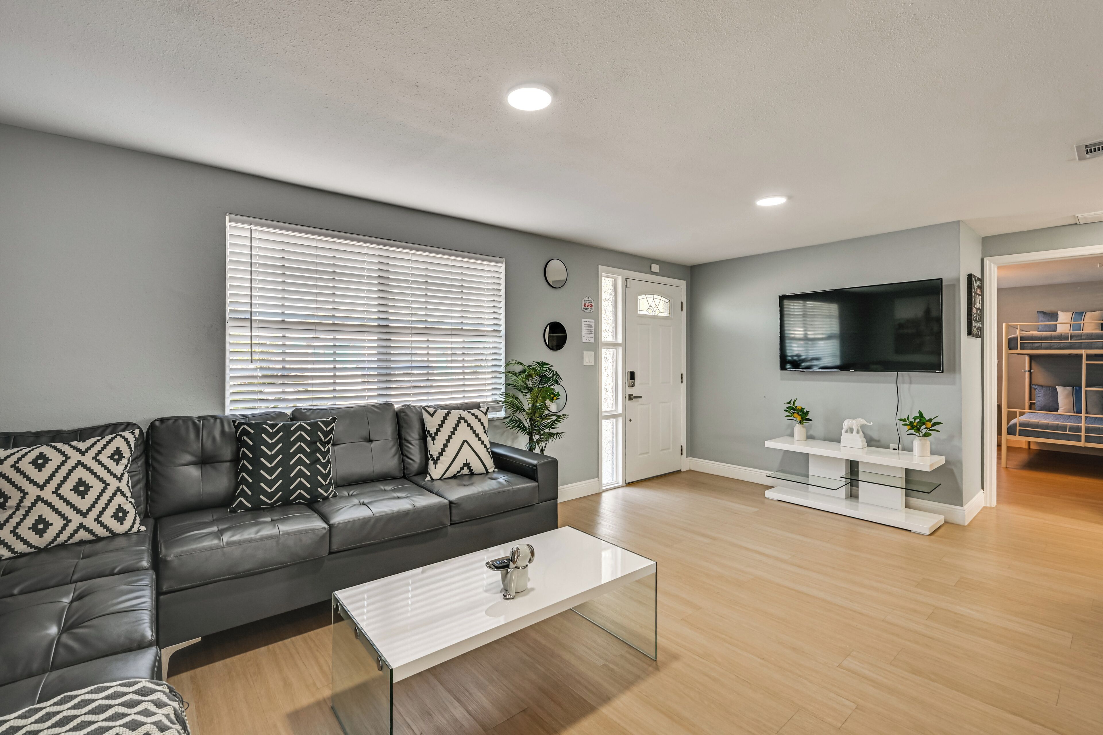 A modern living room with a leather sofa, a white coffee table, a TV, and a wooden floor.