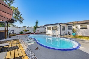Ein Garten mit Schwimmbad, Holzterrasse und weißem Zaun.
