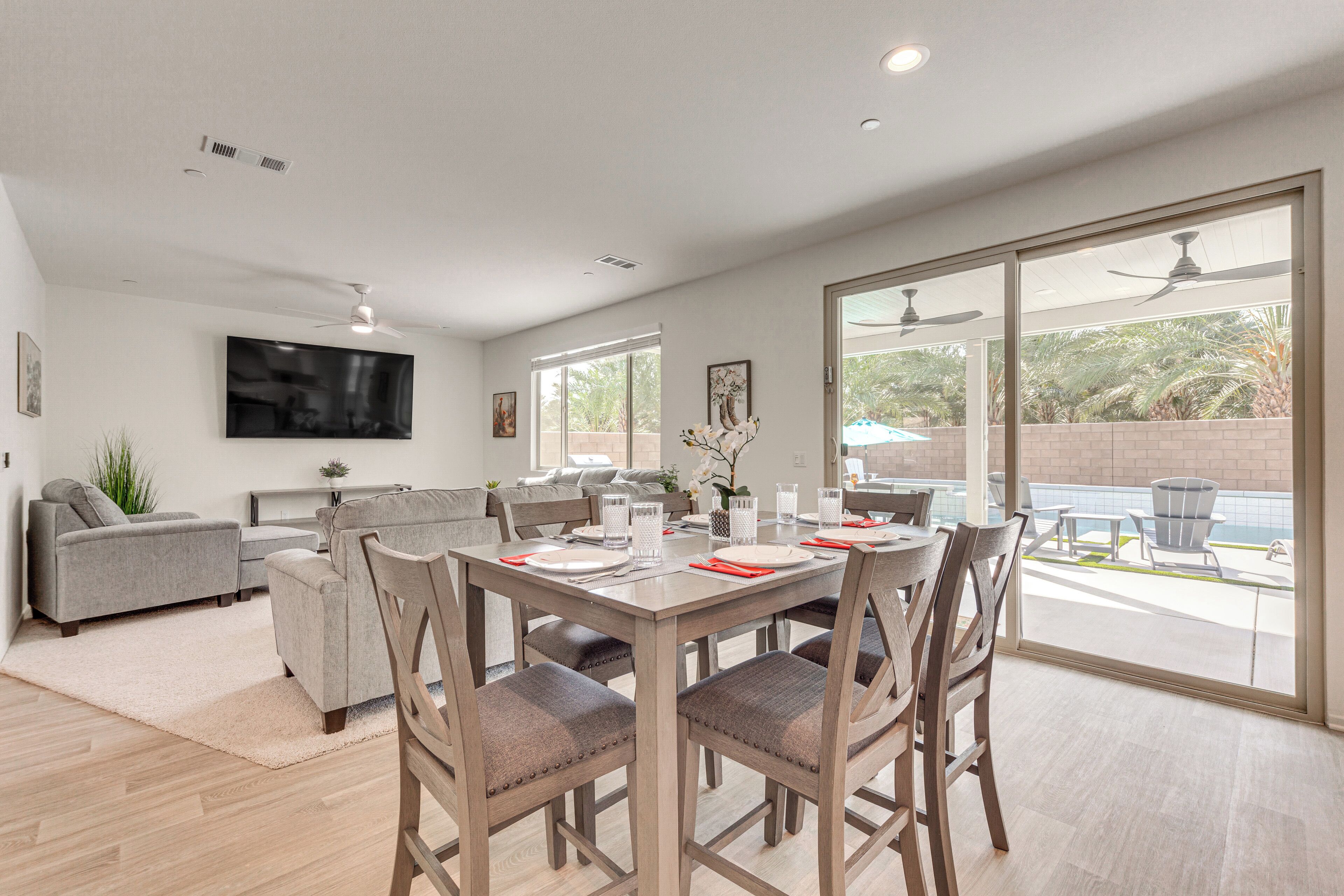 A modern living room with a dining table, chairs, sofas, and a TV mounted on the wall.