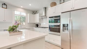 A modern kitchen with white cabinetry, a stainless steel refrigerator, and a central island.