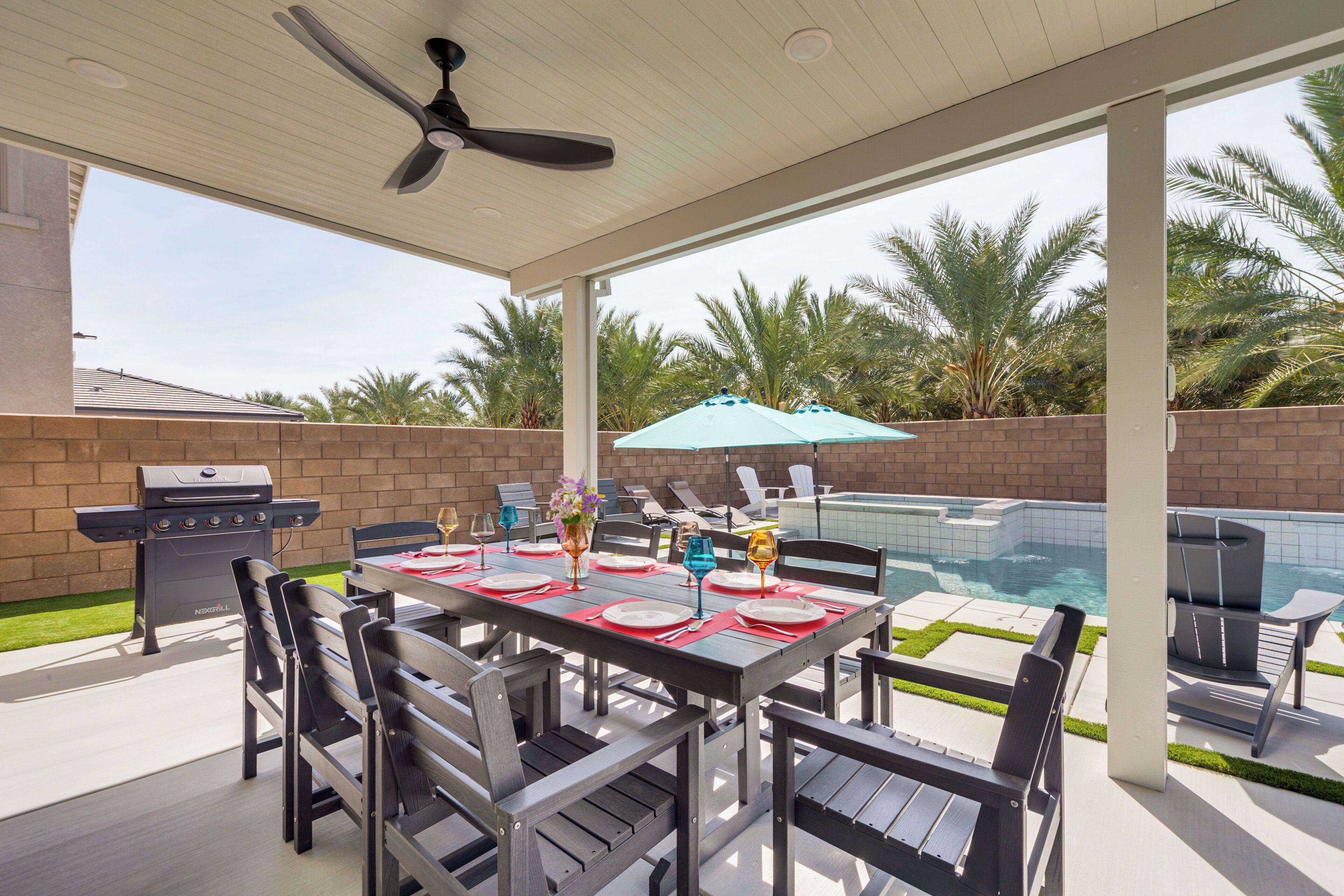Un patio al aire libre con piscina, una parrilla y sillas de descanso.