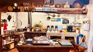 A rustic kitchen with wooden shelves, a buffet table, and various kitchen utensils. - Casas Da Ribeira (Seia)