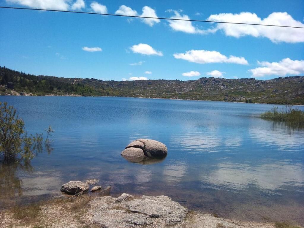 Un lago tranquilo con aguas cristalinas, rodeado de colinas y un cielo despejado.