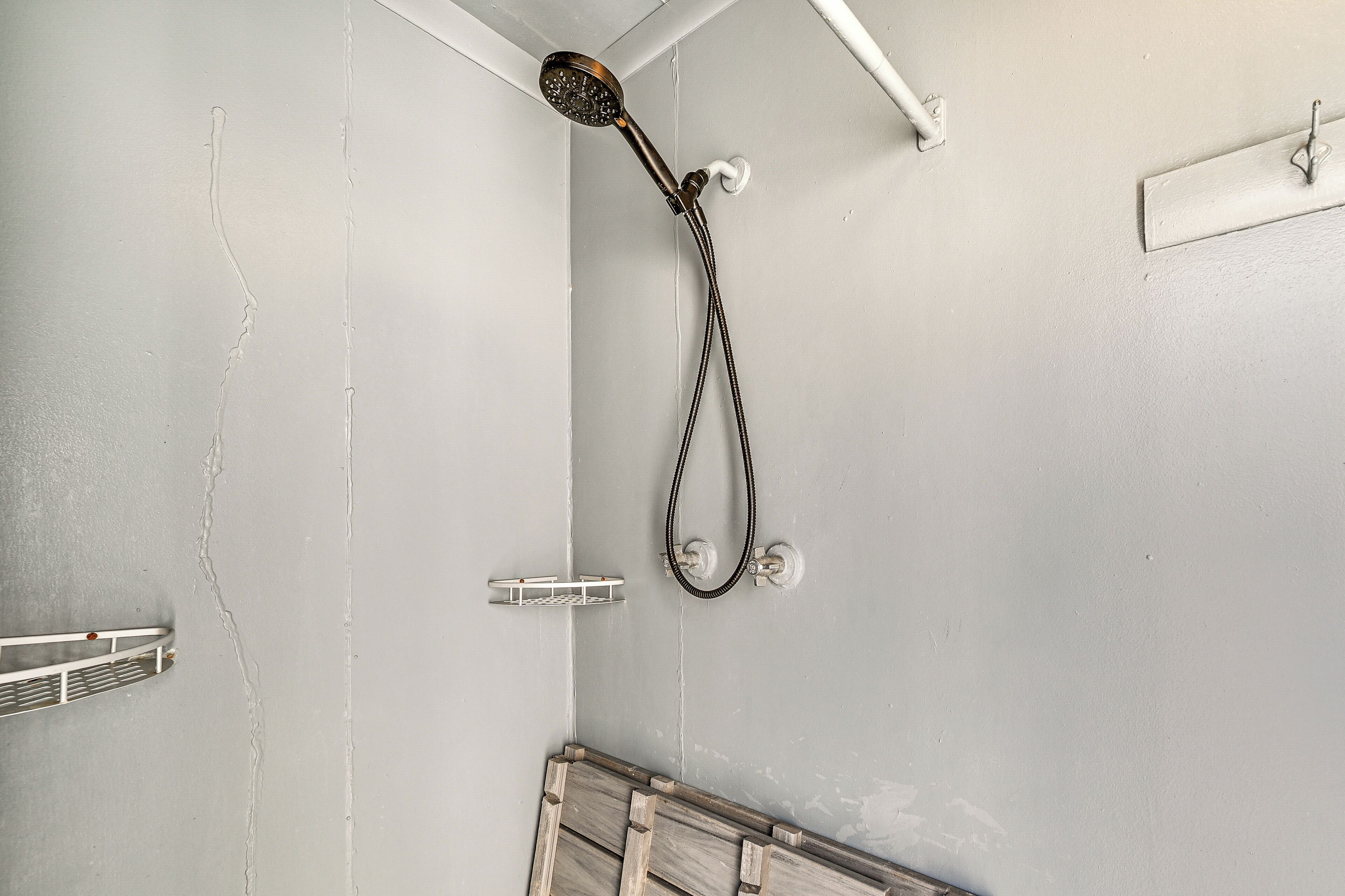 Eine Dusche mit Handbrause, einem Haltegriff für Handtücher aus Metall und einem aus Holz.