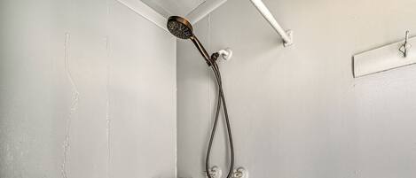 Eine Dusche mit Handbrause, einem Haltegriff für Handtücher aus Metall und einem aus Holz.