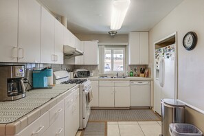 A compact kitchen with white cabinets, a coffee maker, a microwave, and a refrigerator. - Home in San Diego Area w/ Outdoor Entertainment! (Spring Valley)