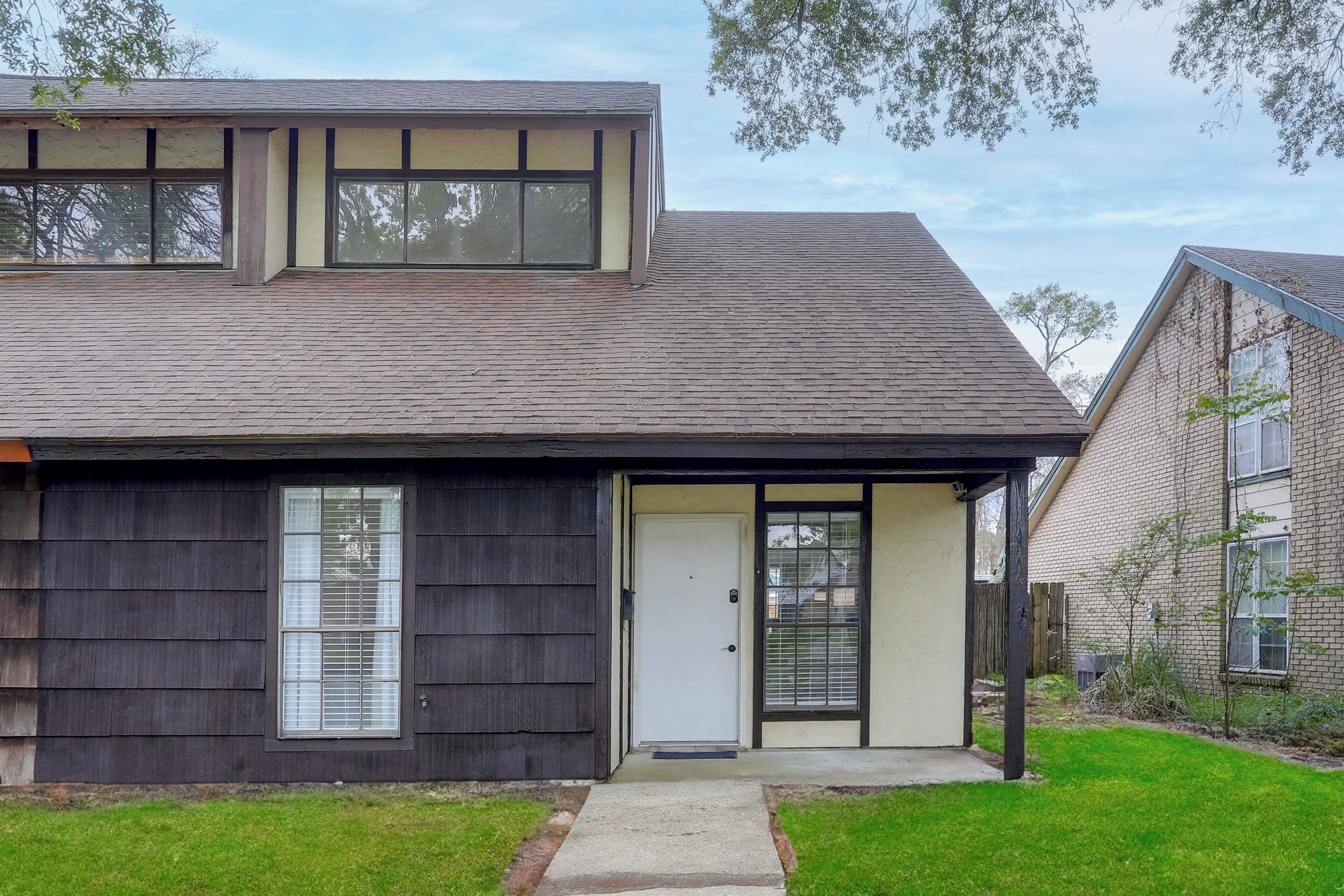 A two-story house with a dark siding exterior, a front door, and a small front yard.