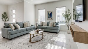 A modern living room with two grey sofas, a coffee table, and a wooden sideboard. - Modern 3BR Retreat - Near Bluebonnet & Hospitals (Baton Rouge)