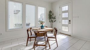 A dining area with a round table, wooden chairs, a vase with flowers, and a door with frosted glass panels. - Modern 3BR Retreat - Near Bluebonnet & Hospitals (Baton Rouge)