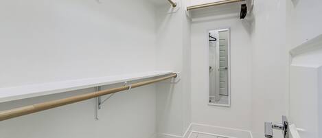 A bathroom with white walls, a wooden handrail, a mirror, and a white door.