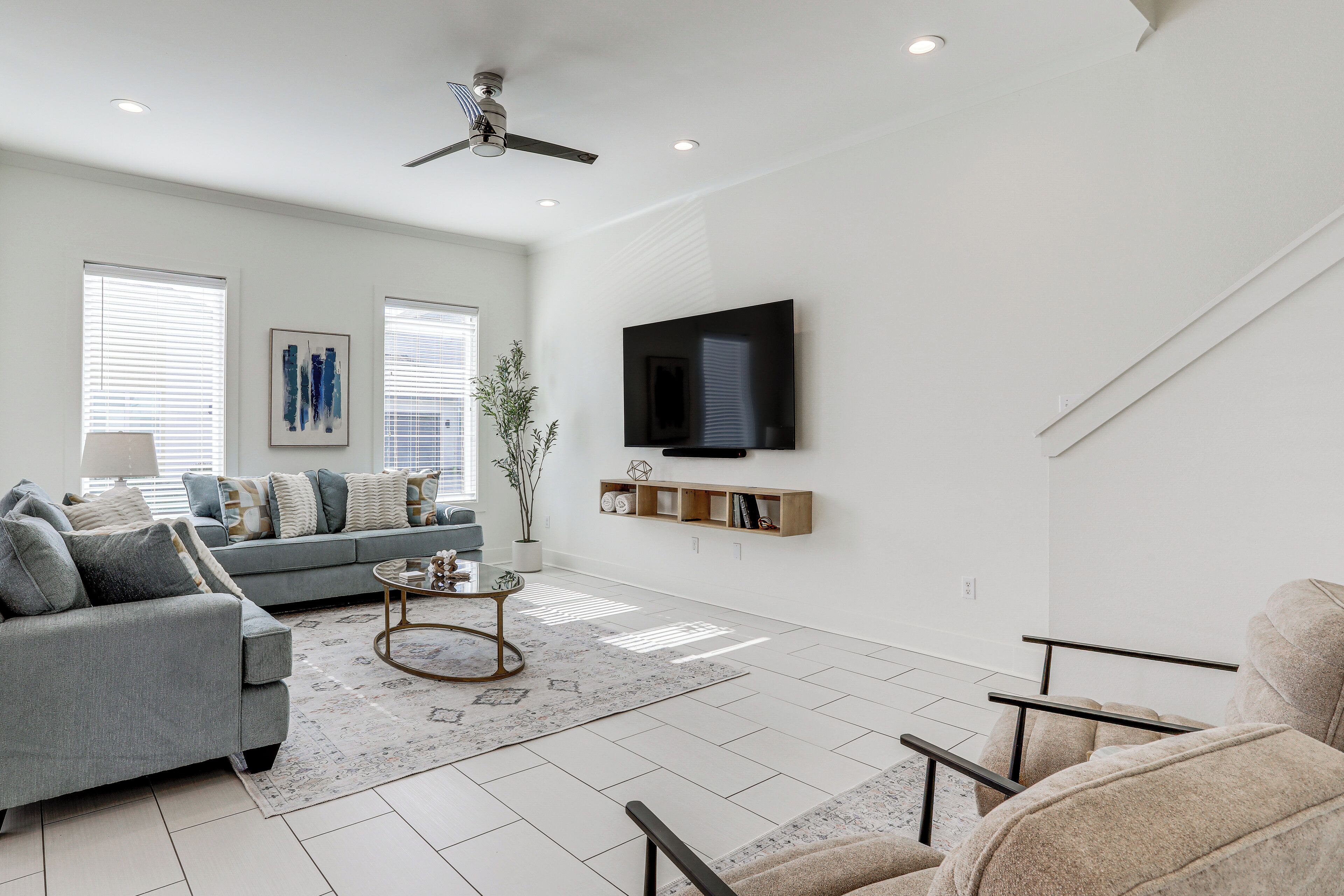 A modern living room with a grey sofa, a coffee table, and a TV mounted on the wall.