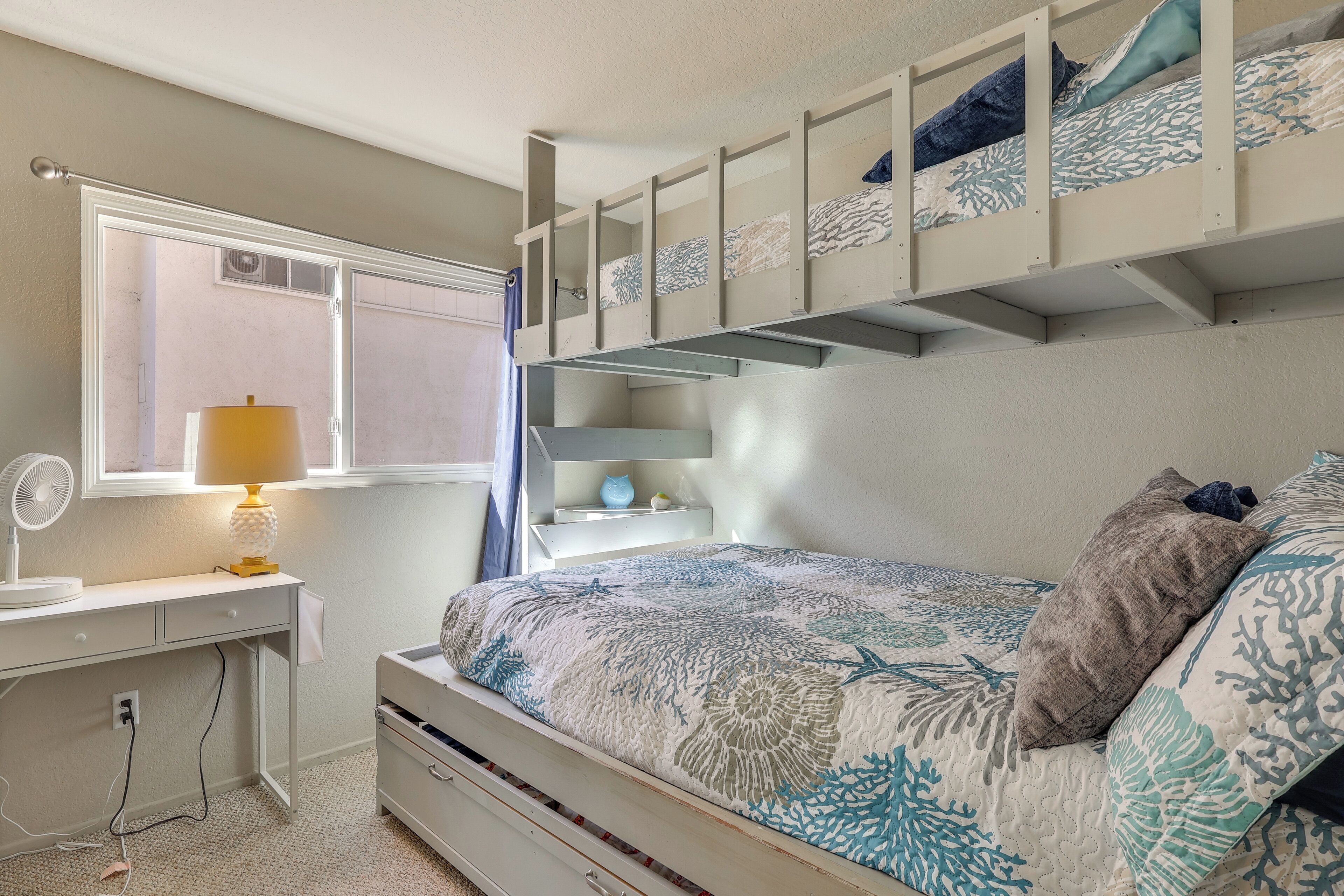 Ein Schlafzimmer mit einem Etagenbett, einem Schreibtisch mit Lampe und einem Fenster.