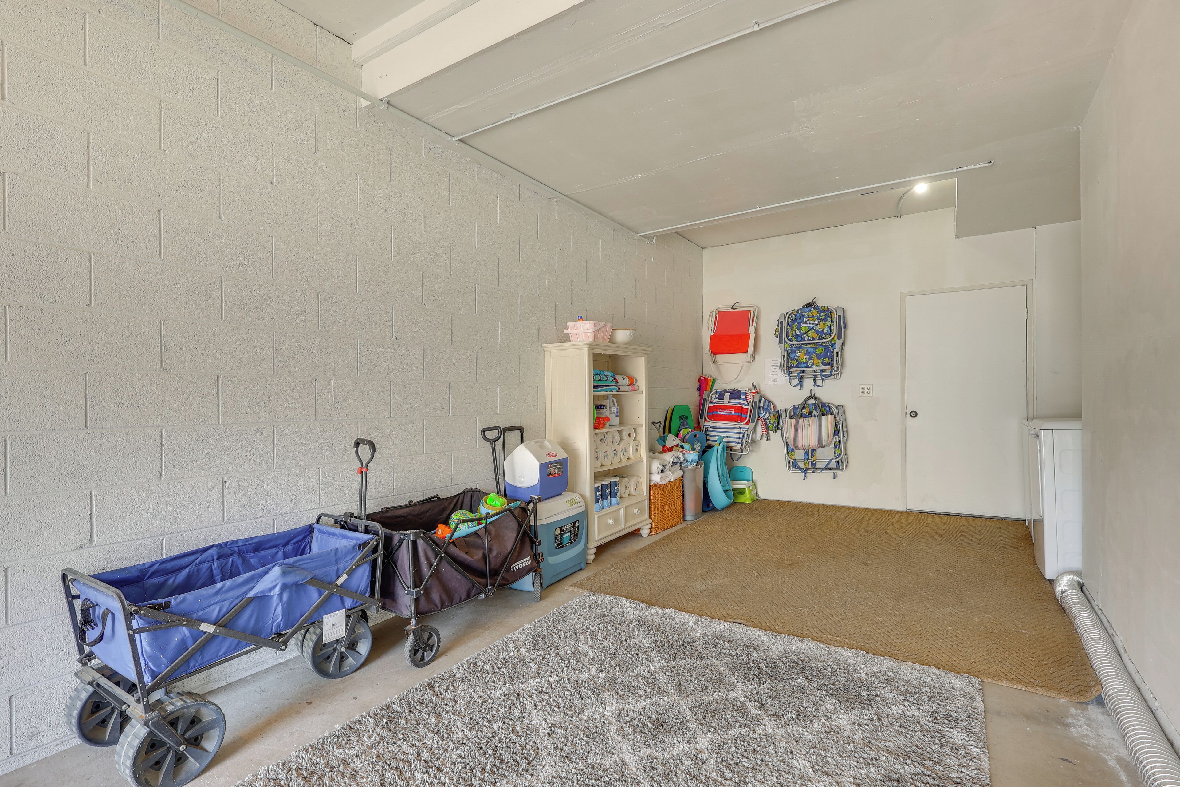 A room with a concrete block wall, a blue cart, a white cabinet, and a door.