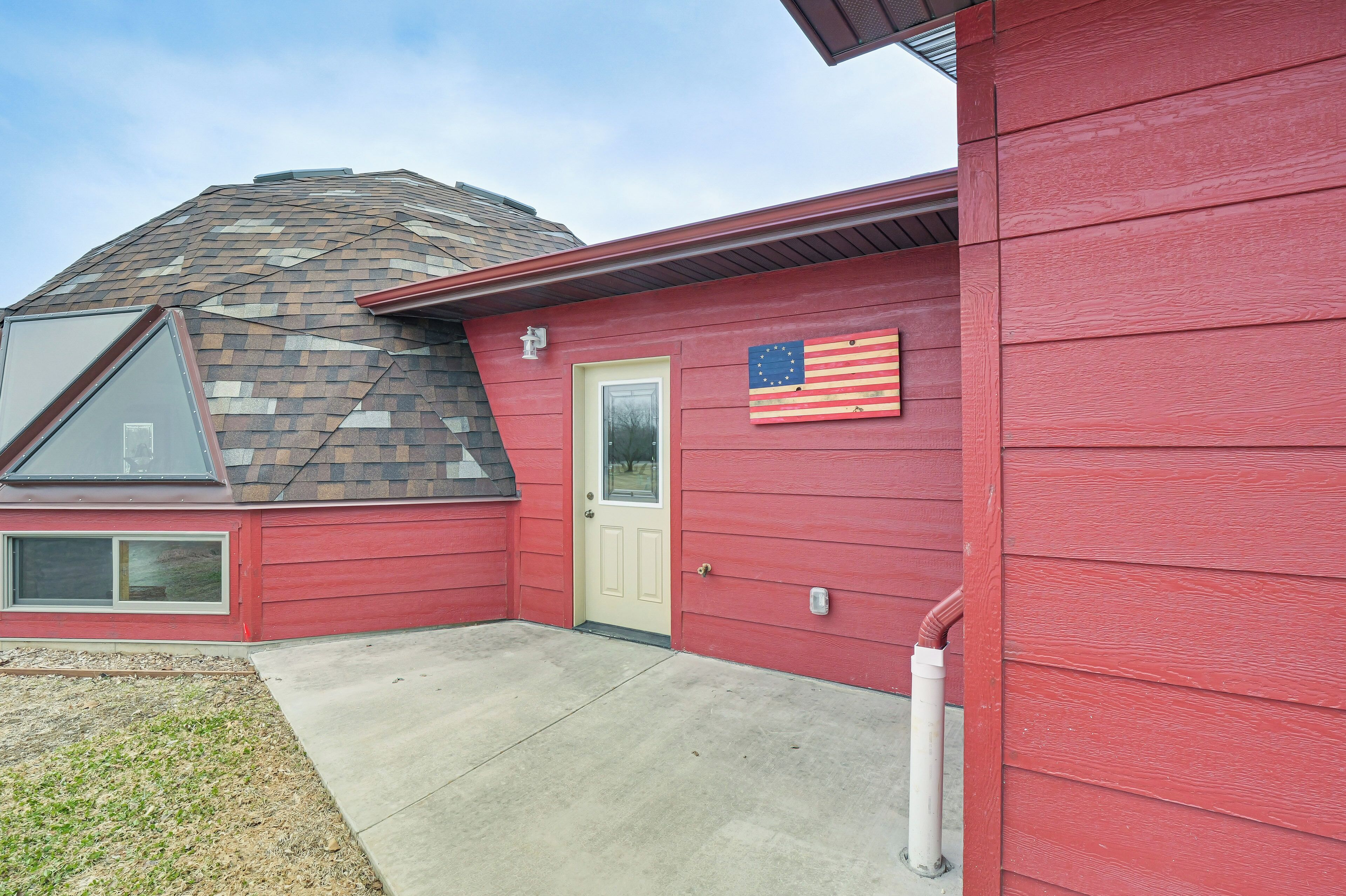 A red house with a beige door, a small window, and an American flag.