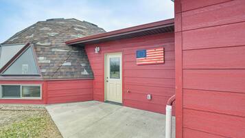 A red house with a beige door, a small window, and an American flag.