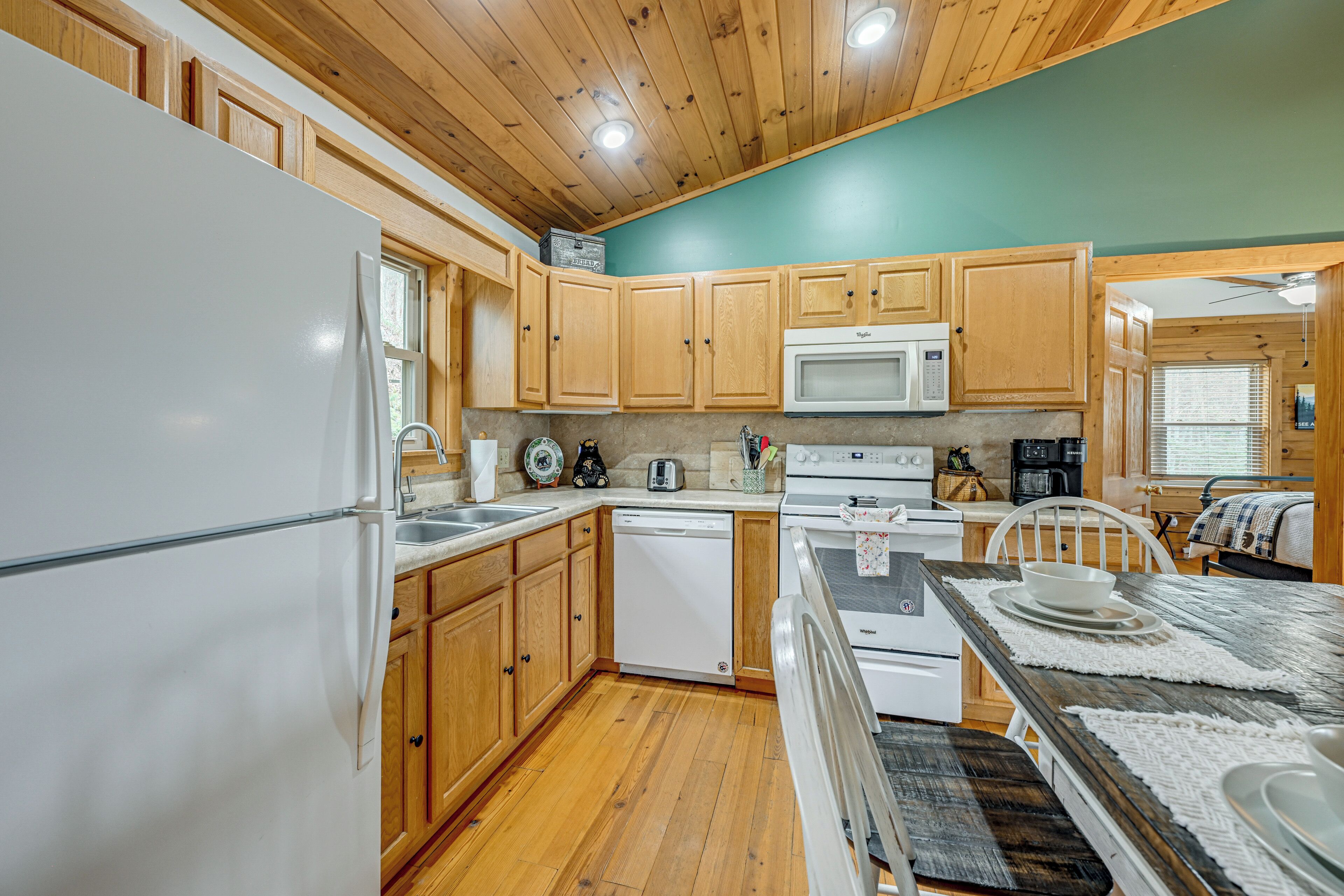 A kitchen with wooden cabinets, a white refrigerator, a dishwasher, a microwave, and a stove.