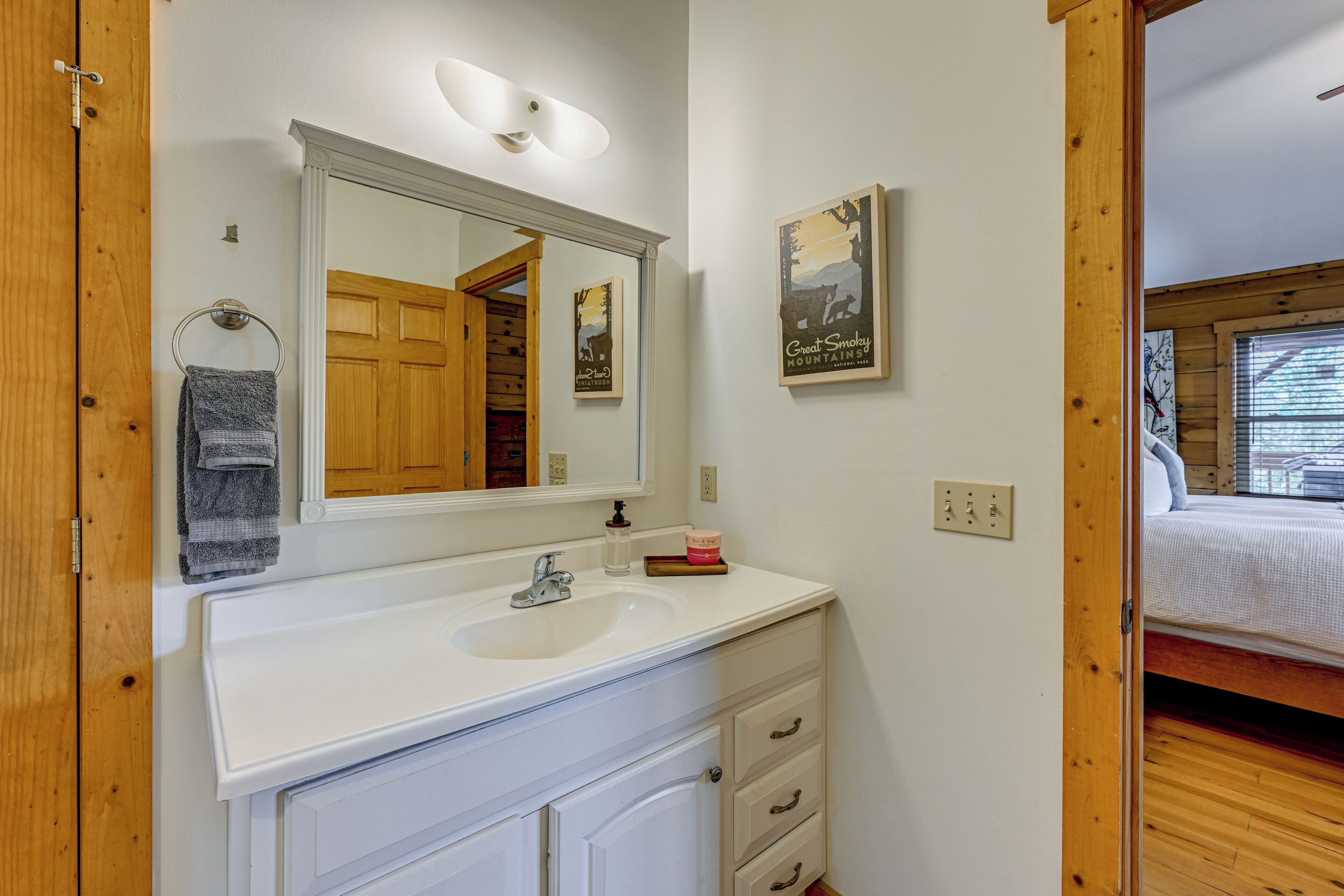 A bathroom with a white sink, mirror, and wooden door.