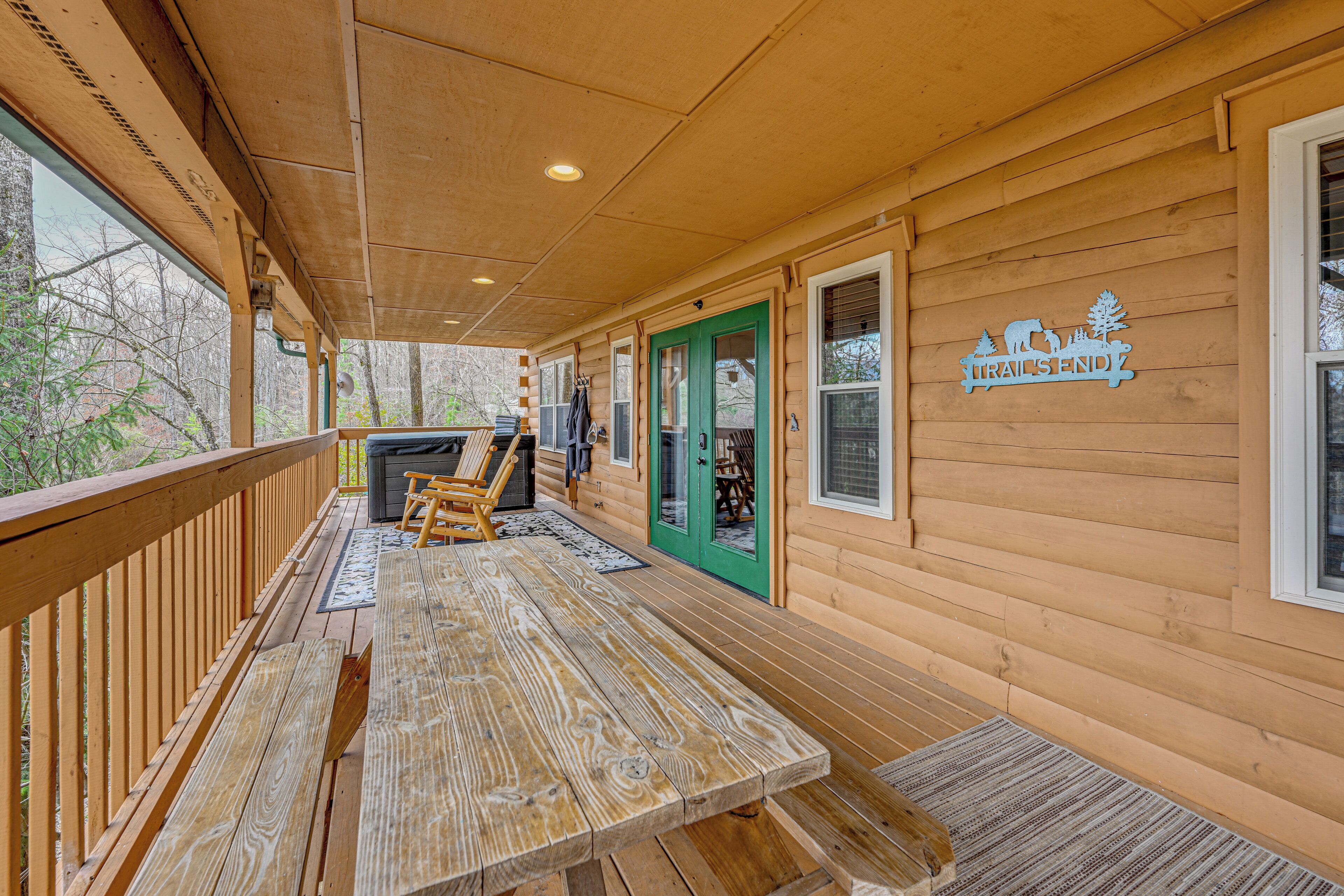 A wooden deck with a picnic table, a grill, and a sign reading 'TRAILSEND.'