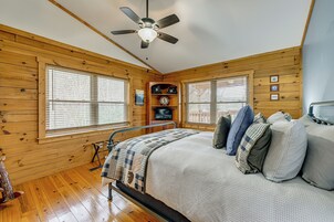 Una habitación con paneles de madera, una cama, un ventilador de techo y un televisor.