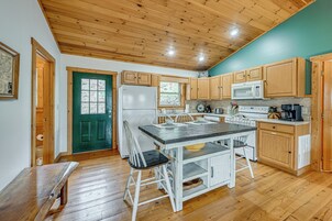A kitchen with wooden cabinets, a white refrigerator, a microwave, and a dining table with chairs.