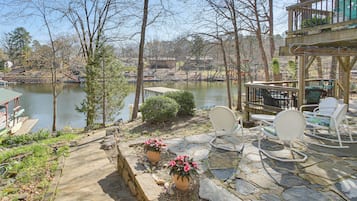 A lakeside patio with stone flooring, potted plants, and outdoor furniture.