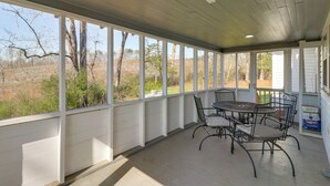 A covered patio with a table and chairs, large windows, and a view of the outdoors. - Pet-friendly 'railroad Cottage' Near Wedowee Lake (Lineville)