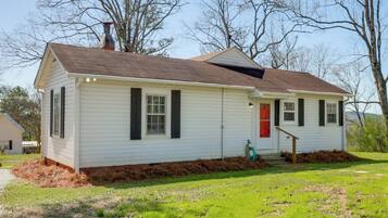 A single-story house with a brown roof, white siding, and a red door.