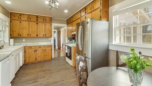 A kitchen with wooden cabinets, a stainless steel refrigerator, and a dining table with a vase. - Pet-friendly 'railroad Cottage' Near Wedowee Lake (Lineville)