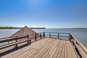 Un muelle de madera que se adentra en un cuerpo de agua tranquilo, bajo un cielo despejado.