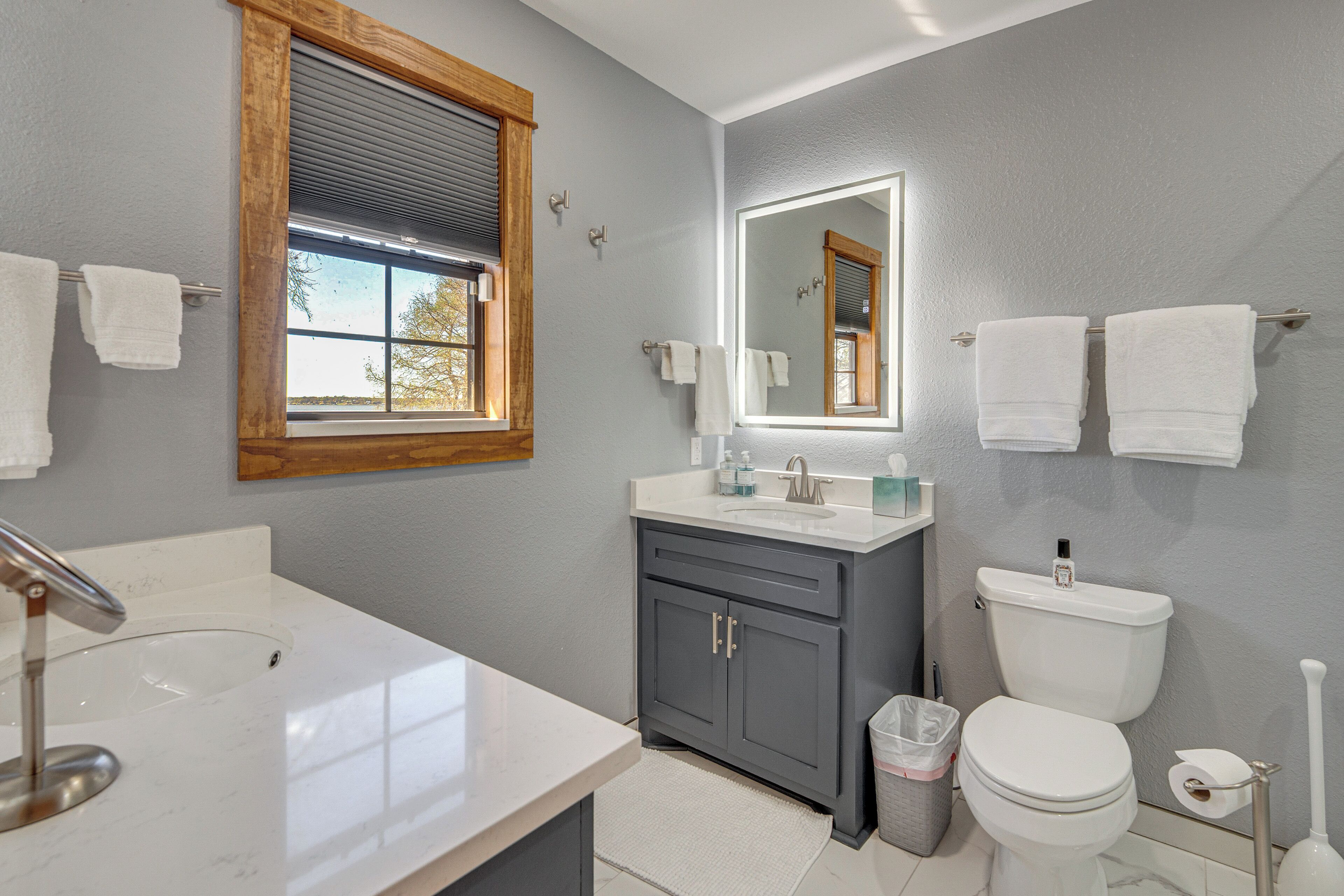 Ein Badezimmer mit Waschbecken, Spiegel, Toilette und Fenster.