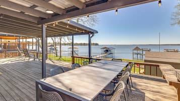 A covered outdoor deck with tables and chairs, overlooking a body of water.