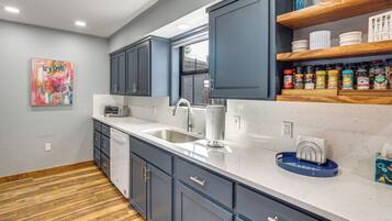 A modern kitchen with grey cabinets, a white countertop, and a wooden floor.