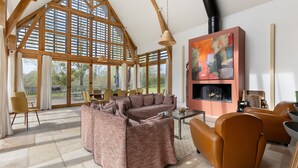 Amplia sala de estar con un sofá modular grande, una chimenea y un comedor con sillas y mesas.