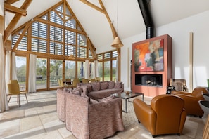 Amplia sala de estar con un sofá modular grande, una chimenea y un comedor con sillas y mesas.