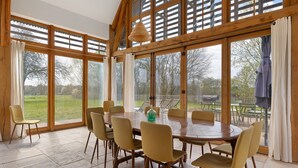 Un comedor amplio con una mesa y sillas de madera, ventanas grandes y vistas al exterior.
