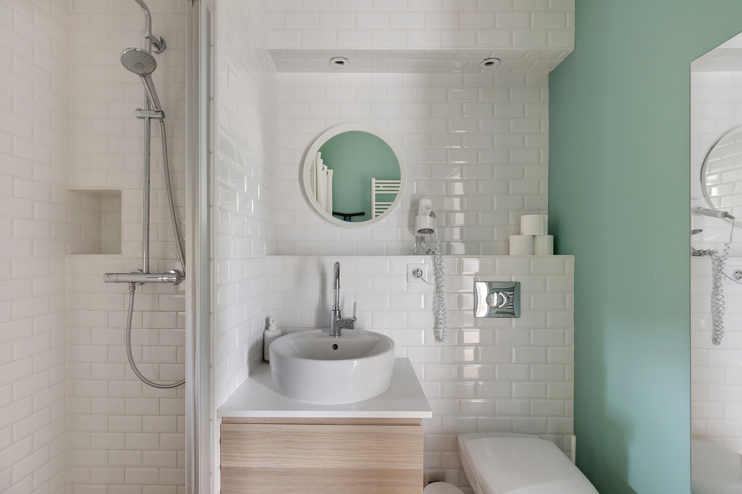 Un baño moderno con lavamanos, espejo y ducha blancos.
