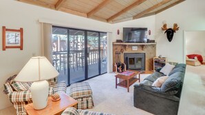 A cozy living room with a fireplace, plaid furniture, and a television.