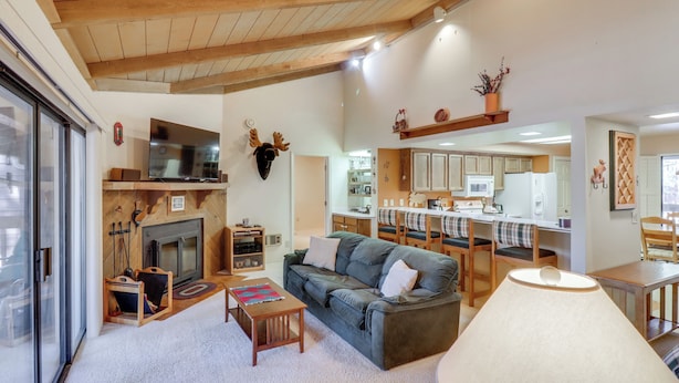 A cozy living room with a fireplace, sofa, and a dining area with a table and chairs.