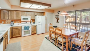 A kitchen with wooden cabinets, a white refrigerator, a microwave, and a dining table with chairs.