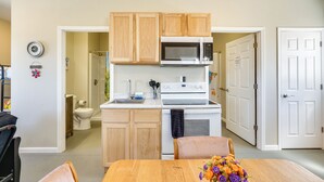 A compact kitchen with wooden cabinets, a microwave, and a stove. - Hike & Fish! Ozarks Studio on Multi-unit Farm (Richland)