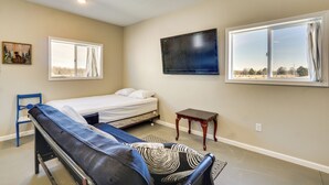 A bedroom with a bed, a bench, a TV, and a window. - Hike & Fish! Ozarks Studio on Multi-unit Farm (Richland)