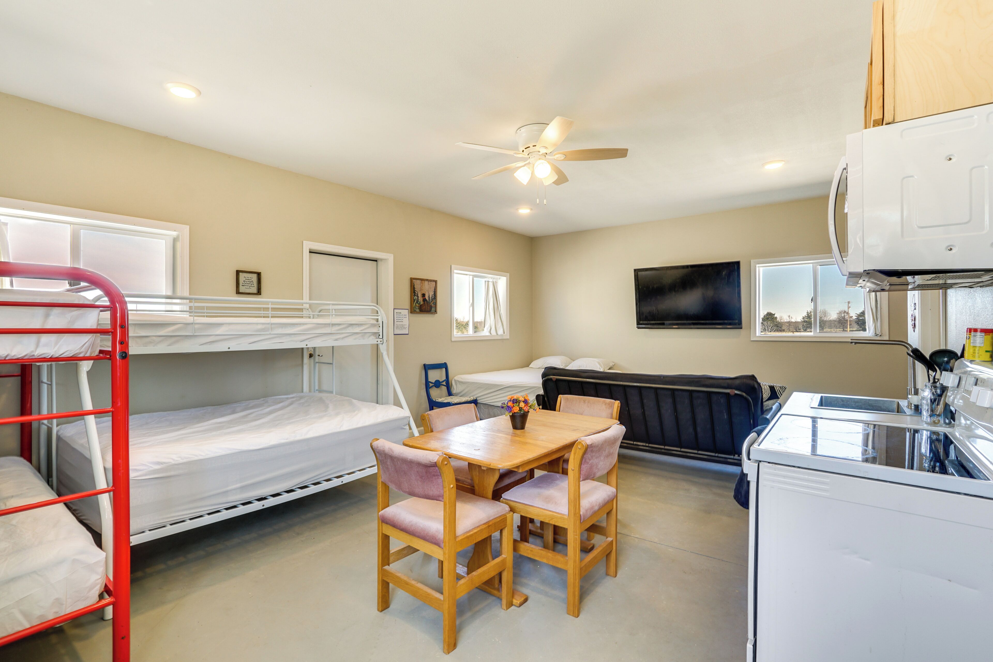 A bunk bed, a dining table with chairs, a ceiling fan, a radiator, and a microwave.