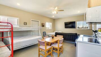 A bunk bed, a dining table with chairs, a ceiling fan, a radiator, and a microwave.