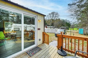 A covered patio with a wooden deck, a sliding glass door leading to a room, and a small outdoor seating area with a table and chairs. - Gateway to Golf Capital! Carthage Escape w/ Pool (Carthage)