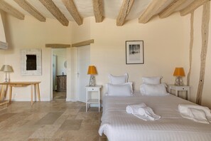Ein Schlafzimmer mit einem großen Bett, zwei Nachttischen mit Lampen, einem Holzboden und einer Tür zu einem anderen Raum.