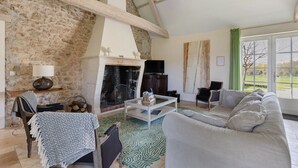 Una sala de estar con chimenea, un sofá, una mesa de centro y vistas al exterior.
