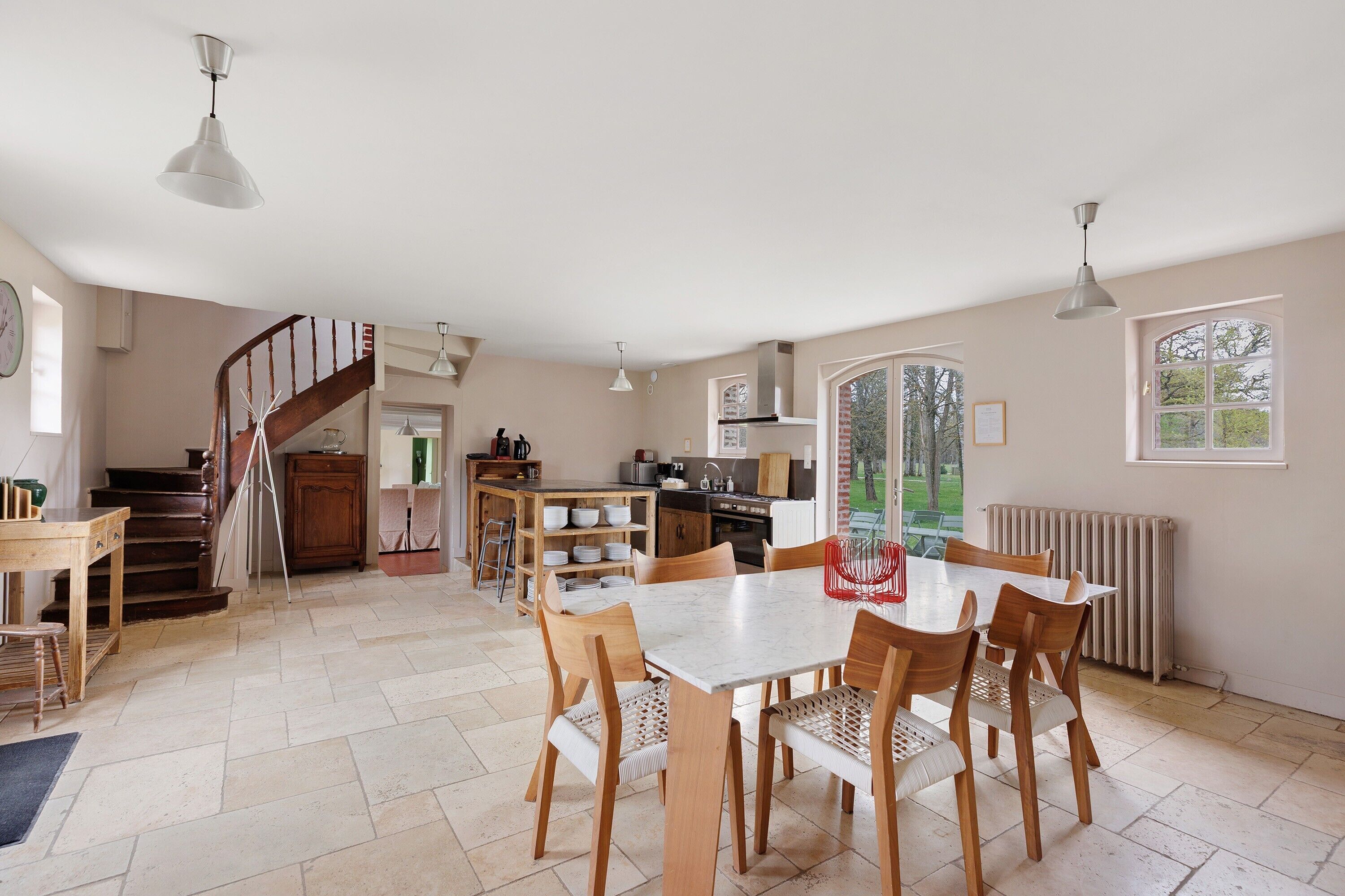 A spacious kitchen with a dining area, a staircase, and a view of the outdoors.